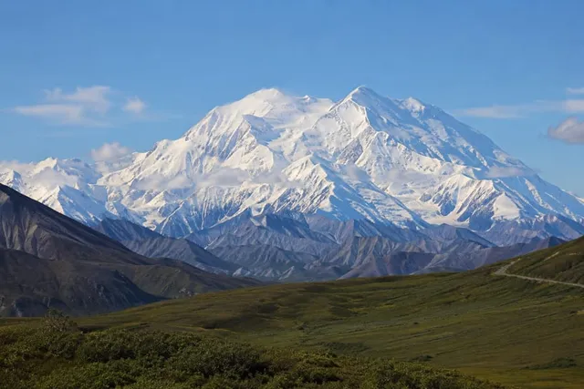Denali's snow-covered massif rising above green tundra and the Alaska Range