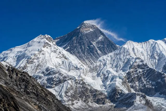 Mount Everest's dark summit pyramid with a snow plume, seen across the Himalaya